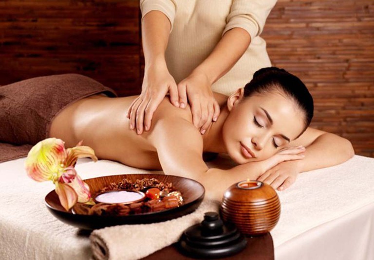 Một người phụ nữ đang nằm thư giãn trong buổi massage body tại nhà với ánh sáng dịu nhẹ.