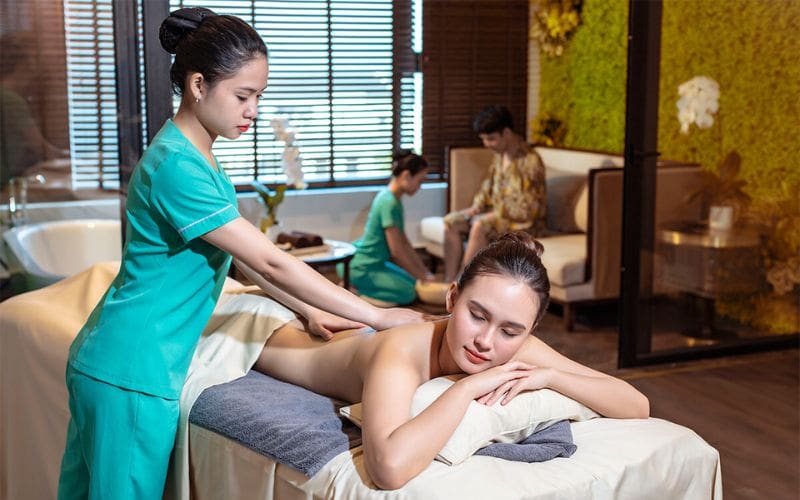 Đôi tay của chuyên viên đang vuốt dài vùng lưng với dầu massage dịu nhẹ.